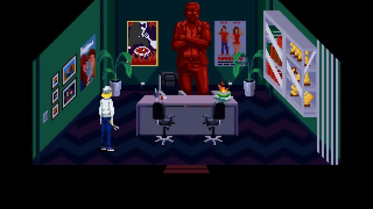 Pixel-art office with a central desk, two visitor chairs, a red statue and a wall display of trophies